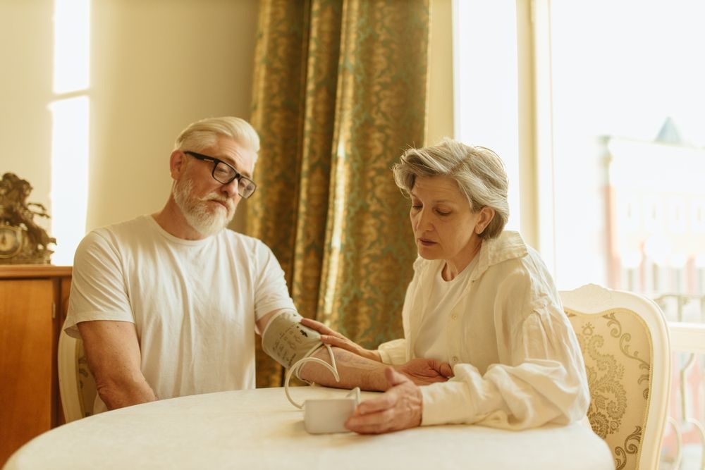 An older couple taking a blood pressure reading at home
