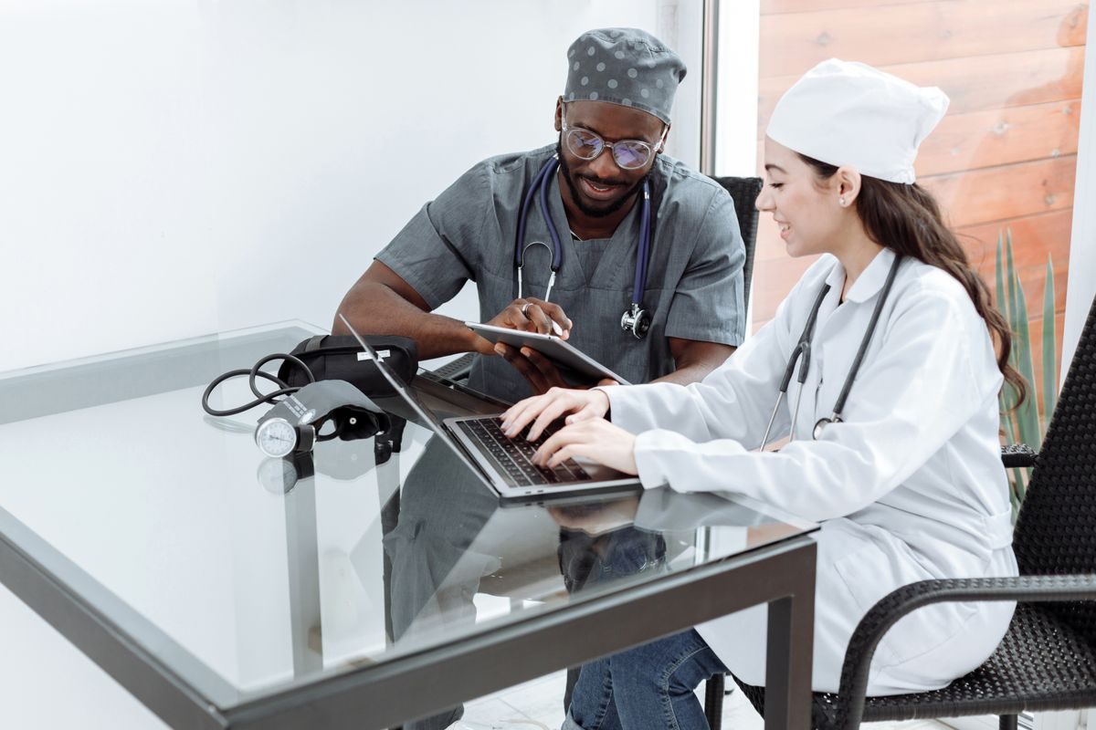 Two clinicians reviewing patient trends on a laptop and tablet