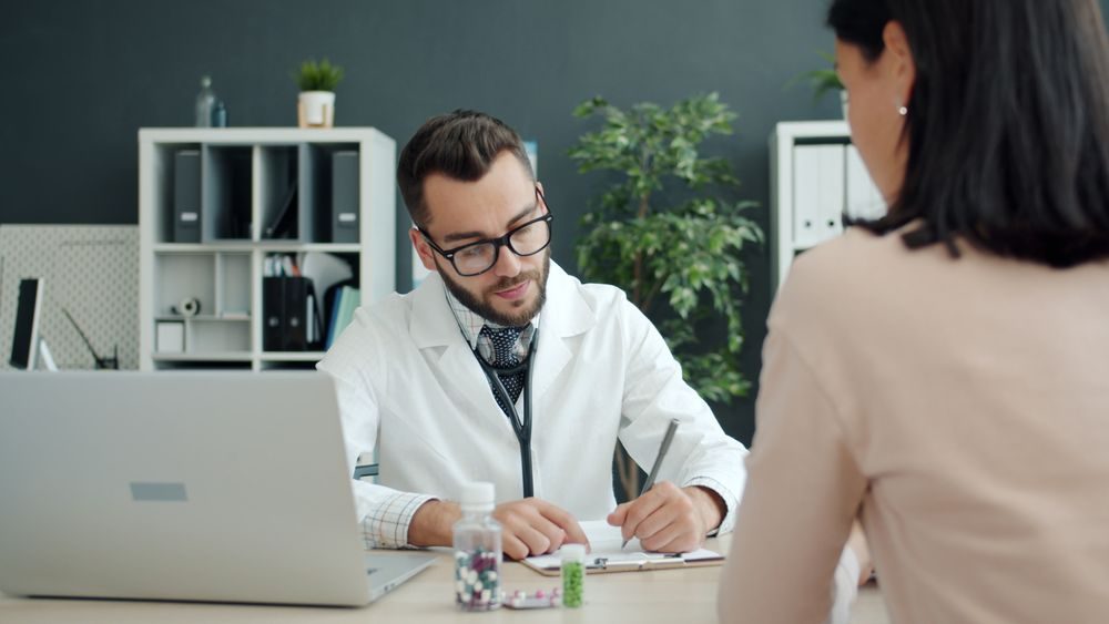 A physician working through a patient record with the patient beside him